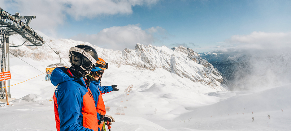 Skifahrer blicken auf Piste ins Tal hinab