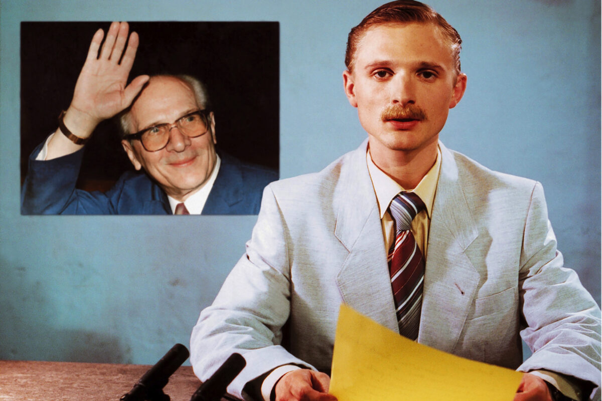 Szenenbild aus dem Film "Good-bye Lenin!": Ein Nachrichtensprecher liest seine Meldungen vor, während ein Bild von Erich Honecker im Hintergrund eingeblendet ist.