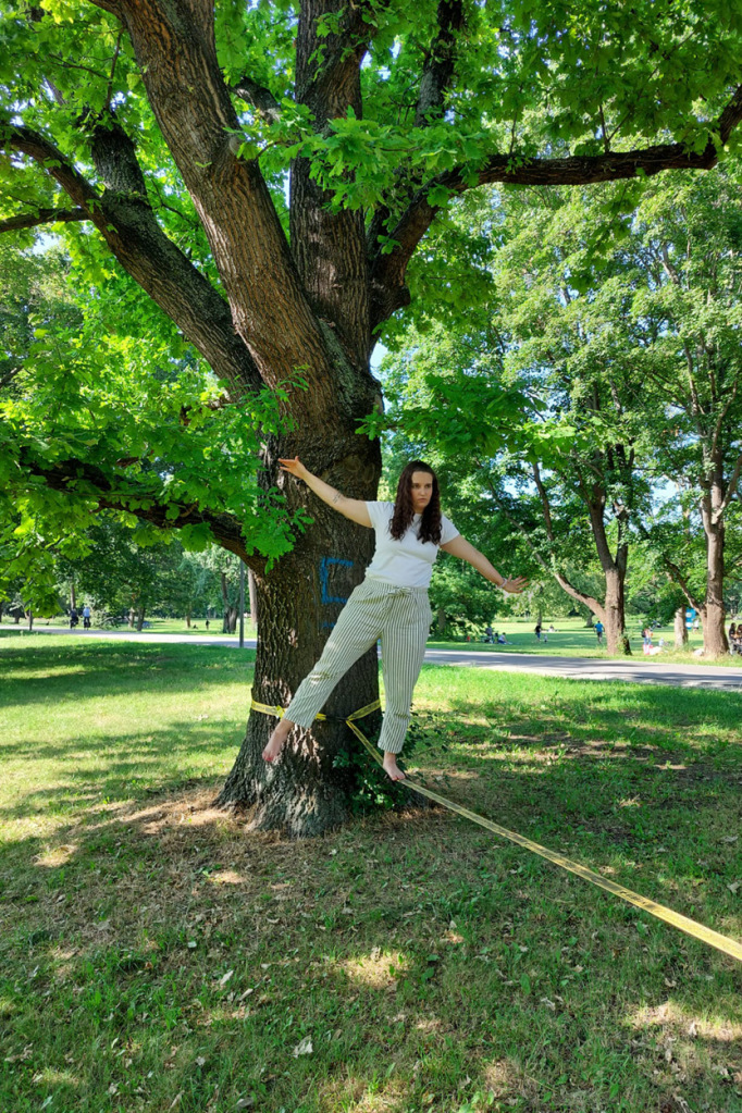 Unsere Autorin balanciert einbeinig auf einer wackeligen Slackline, die zwischen zwei Bäumen aufgespannt wurde.