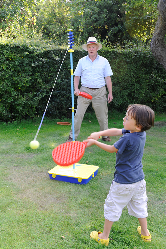 Ein Kind spielt mit seinem Großvater Swingball.
