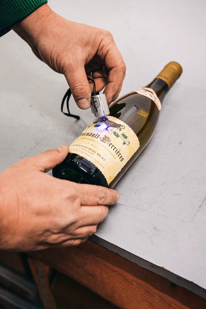 Mit Hilfe eines speziellen Blaulichts wird die unsichtbare Tinte auf den Weinflaschen des Guts Coche-Dury gelesen.