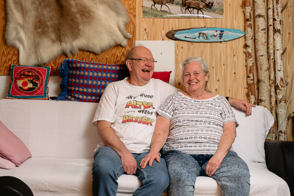 Kay Tietgen sitzt mit seiner Frau auf einem Sofa. Sie lachen.