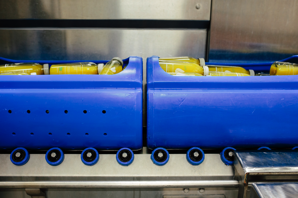 Gelbe Saftflaschen in blauen Kisten auf einem Fließband